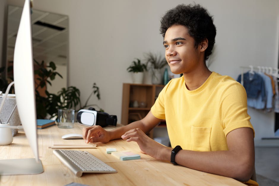Teenager smiling while studying online at home. Modern education setup with computer and VR headset